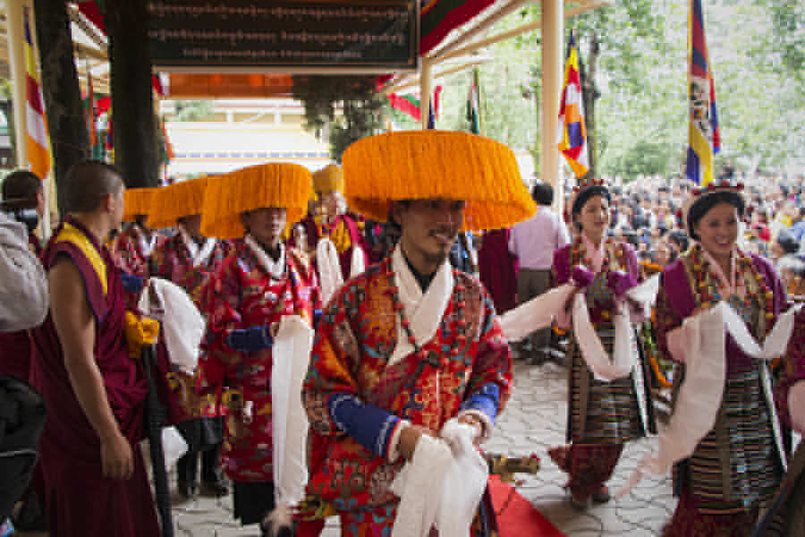Tibeter in traditioneller Tracht folgen Trompeten